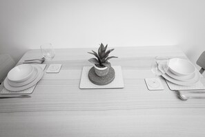 A neatly set dining table with plates, cutlery, and a potted plant.
