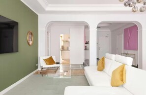 Ein modernes Wohnzimmer mit einem weißen Sofa, einem Glastisch und einer grünen Akzentwand.