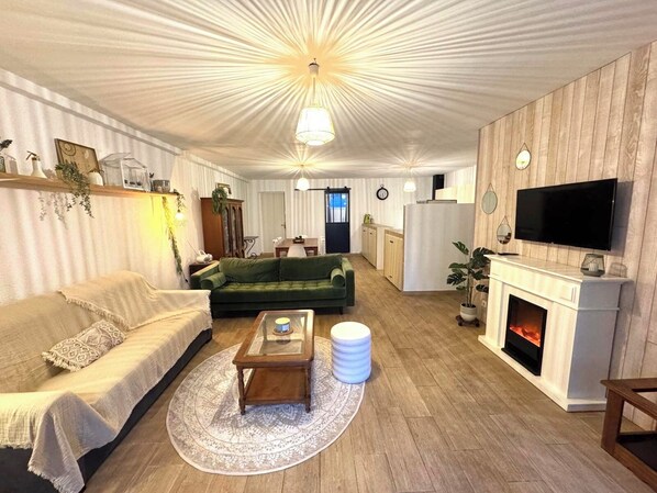 A cozy living room with a green sofa, a wooden coffee table, and a fireplace.