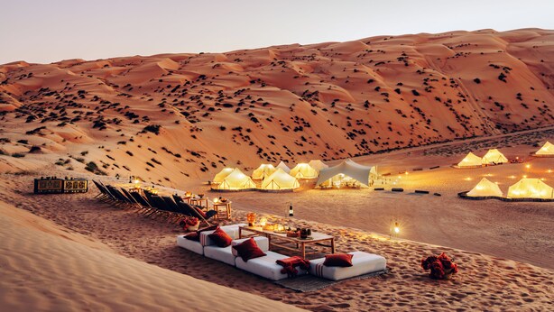 A desert resort with tents, lounge areas, and a dining setup. - Magic Camps Wahiba Sands (Bidiya)