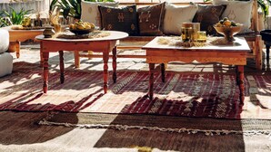 A tented outdoor seating area with tables, chairs, and potted plants. - Magic Camps Wahiba Sands (Bidiya)