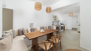 Een moderne, open woonruimte met een houten eettafel, comfortabele zithoek en hanglampen.