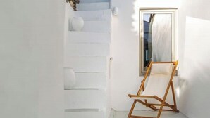 Een witte binnenruimte met een houten schilderstatief en een raam met een witte gordijn.