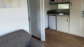 Een kleine keuken met een magnetron, fornuis en spoelbak.