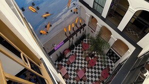 A multi-level atrium with a mural of wheat and ants, checkered flooring, and outdoor seating. - Hotel Divino by Fimedhotels (Figueres)