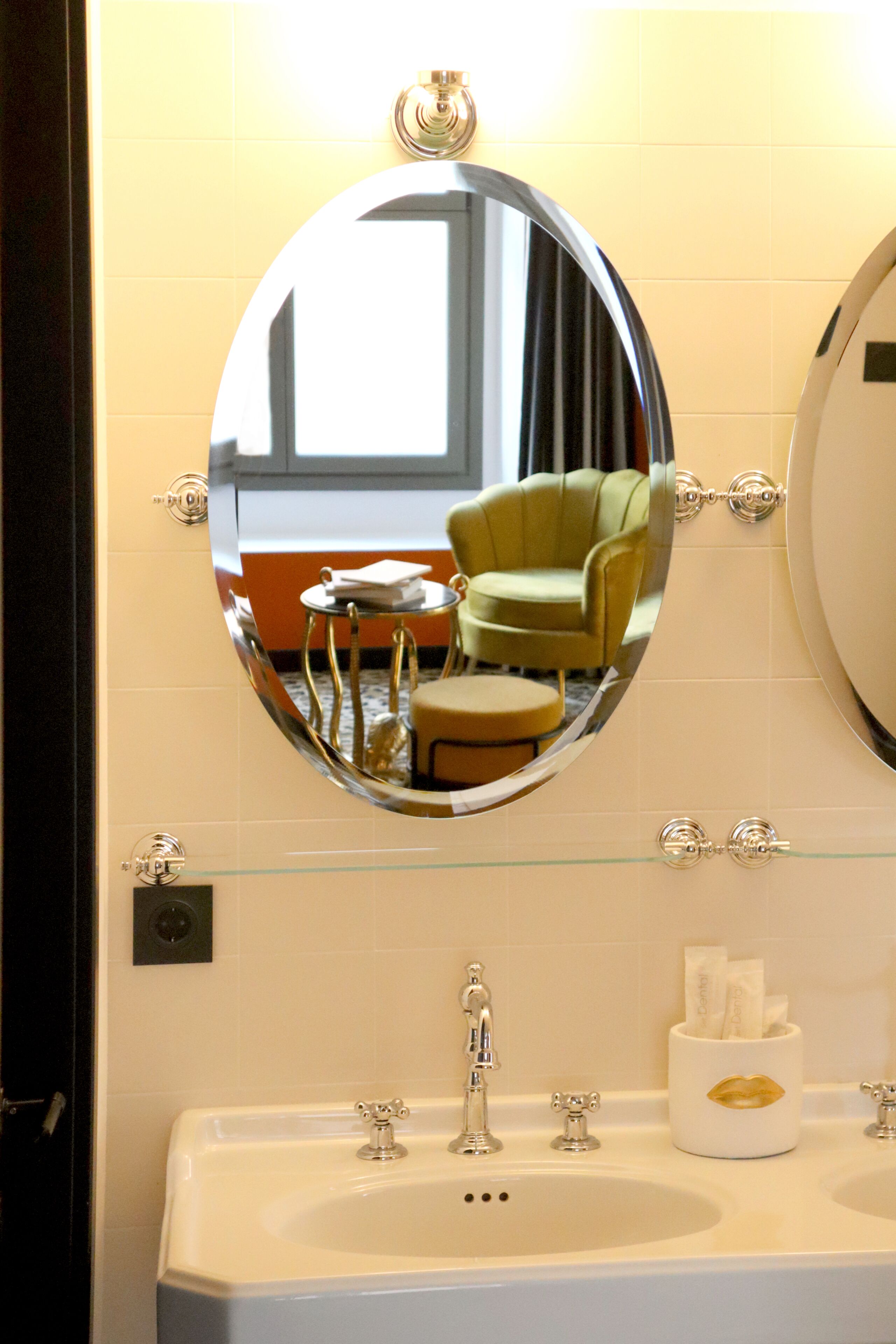 A bathroom with a round mirror, a sink, and a glass shelf.