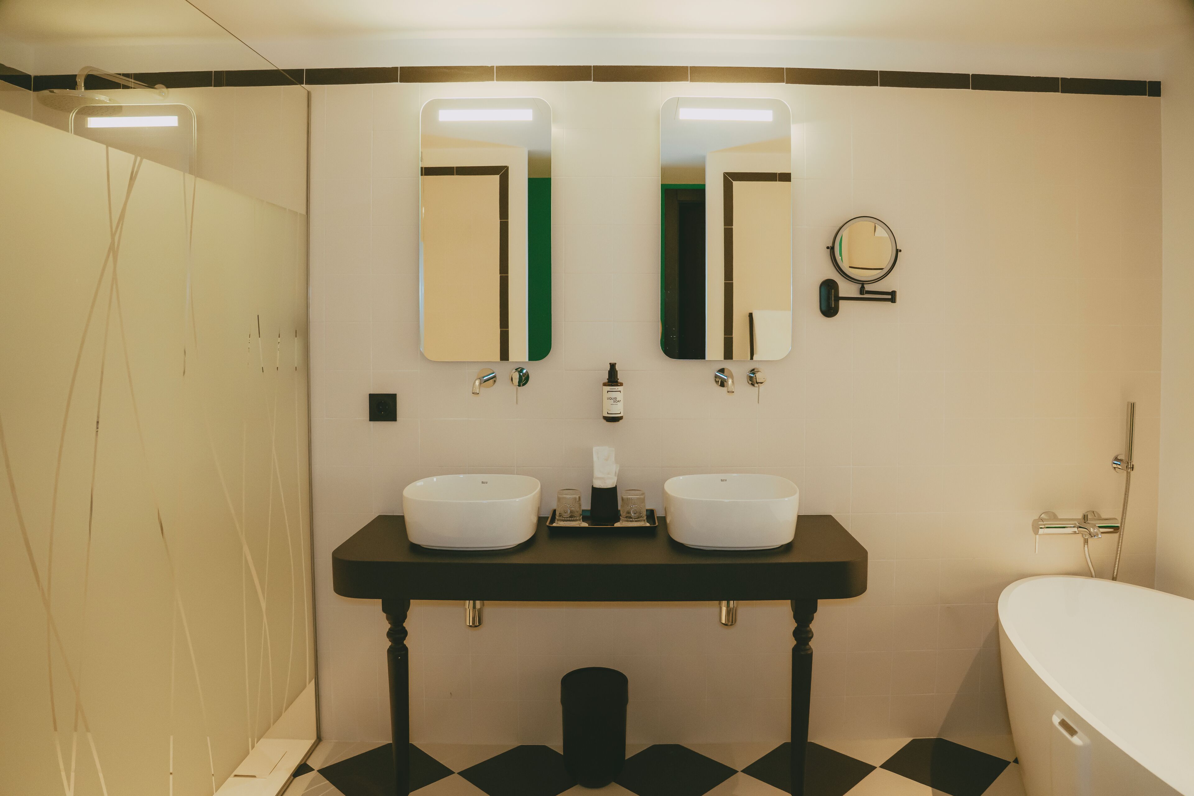 A bathroom with two sinks, a mirror, a toilet, and a bathtub.