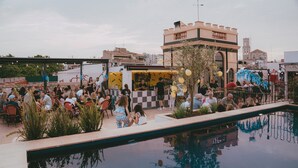 A rooftop pool area with a checkered floor, a bar, and a crowd of people. - Hotel Divino by Fimedhotels (Figueres)