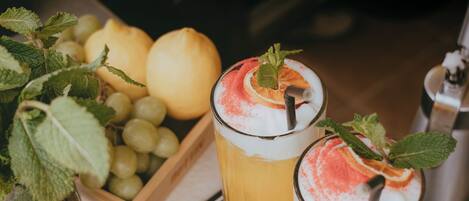 Un bar con dos cócteles, un cuenco de frutas y una botella.