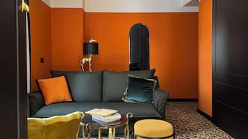A room with a sofa, a small table, a lamp, and a leopard print carpet.