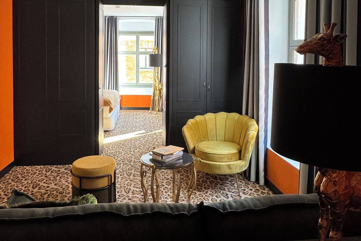 A modern living room with a sofa, a round table, a yellow armchair, and a giraffe statue.