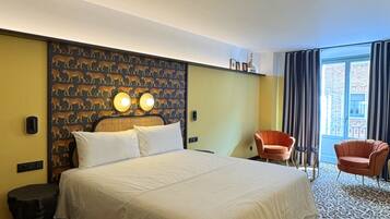 A hotel room with a large bed, two bedside lamps, a leopard print carpet, a chair, and a view of the outside.