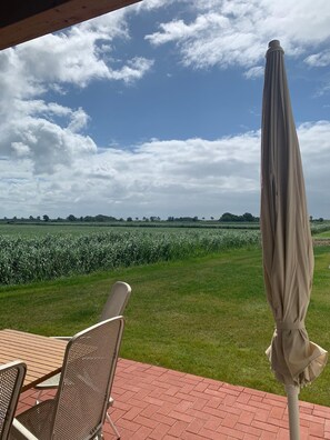 Relax in a serene outdoor seating area with a table and chairs, overlooking a picturesque field.