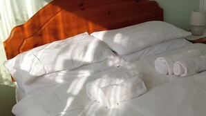 Een net opgemaakt bed met witte lakens en een houten hoofdbord.