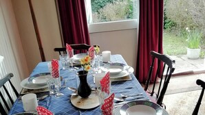 Een eettafel gedekt met borden, glazen, bestek en een vaas met bloemen.