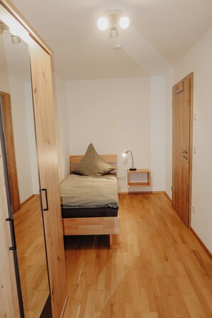 Una camera da letto con un letto in legno, un comodino con una lampada e un armadio.