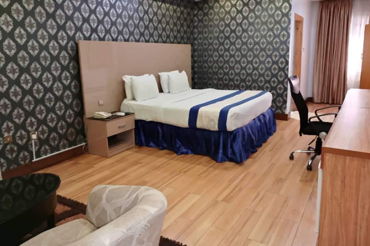A hotel room with a large bed, a desk, and a chair.