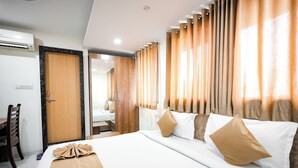 A hotel room with a large bed, wooden headboard, and curtains. - Hotel Konark (Indore)