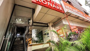 A hotel entrance with a staircase leading to the lobby, a glass facade, and a sign indicating the hotel name. - Hotel Konark (Indore)