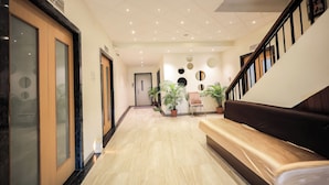 A hotel lobby with a marble floor, a reception desk, potted plants, and a staircase. - Hotel Konark (Indore)