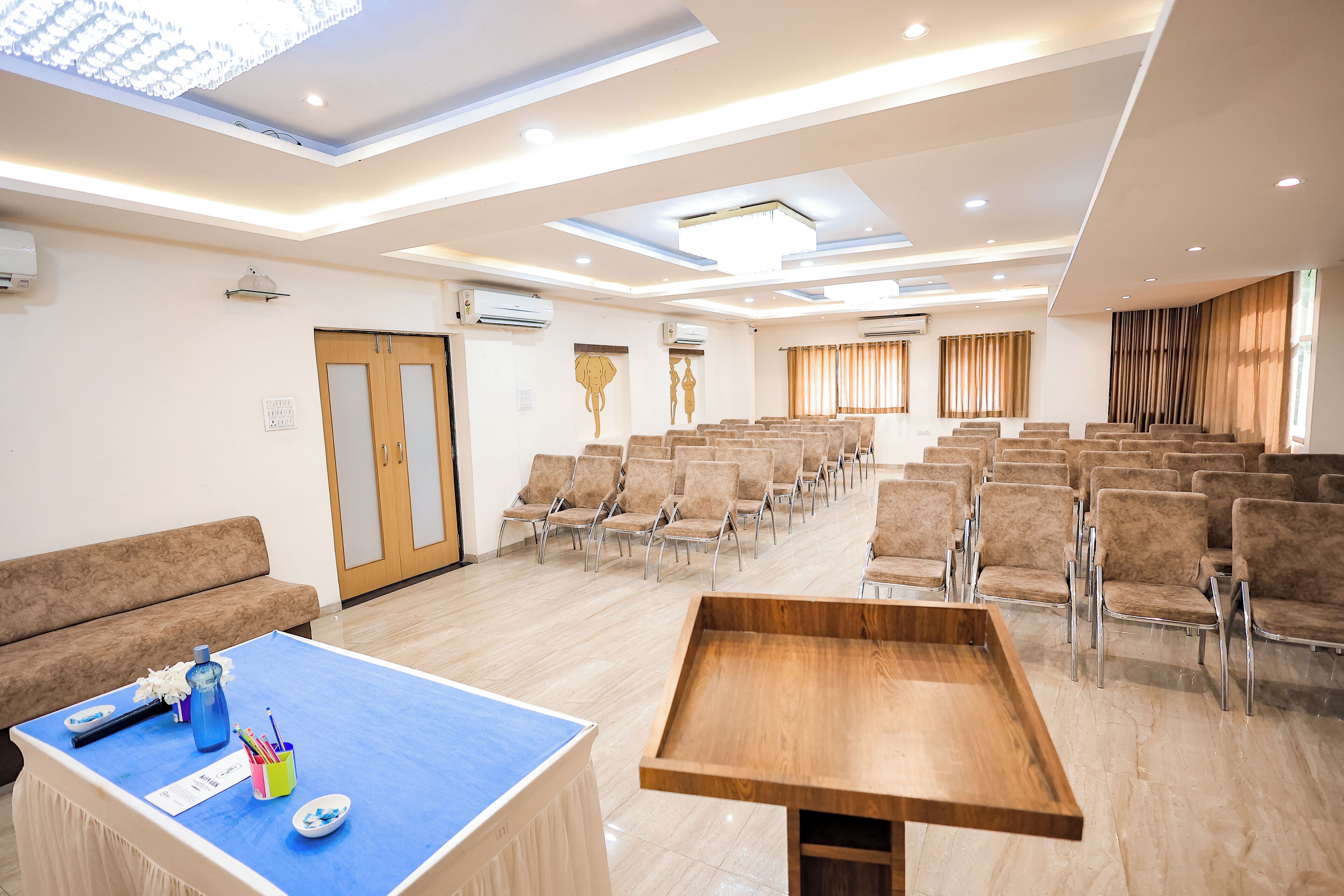 Une salle de conférence avec des rangées de chaises, une table en bois et un canapé.