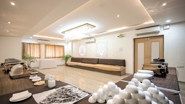 A spacious living area with a modern sofa, a dining table set with plates and cutlery, and a decorative white structure. - Hotel Konark (Indore)