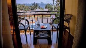 Un balcón con una mesa lista para dos personas, que incluye un plato de comida, una taza y una botella de agua.