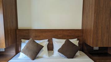 Una cama bien hecha con ropa de cama a rayas y dos almohadas marrones, frente a un cabecero y paredes de madera.