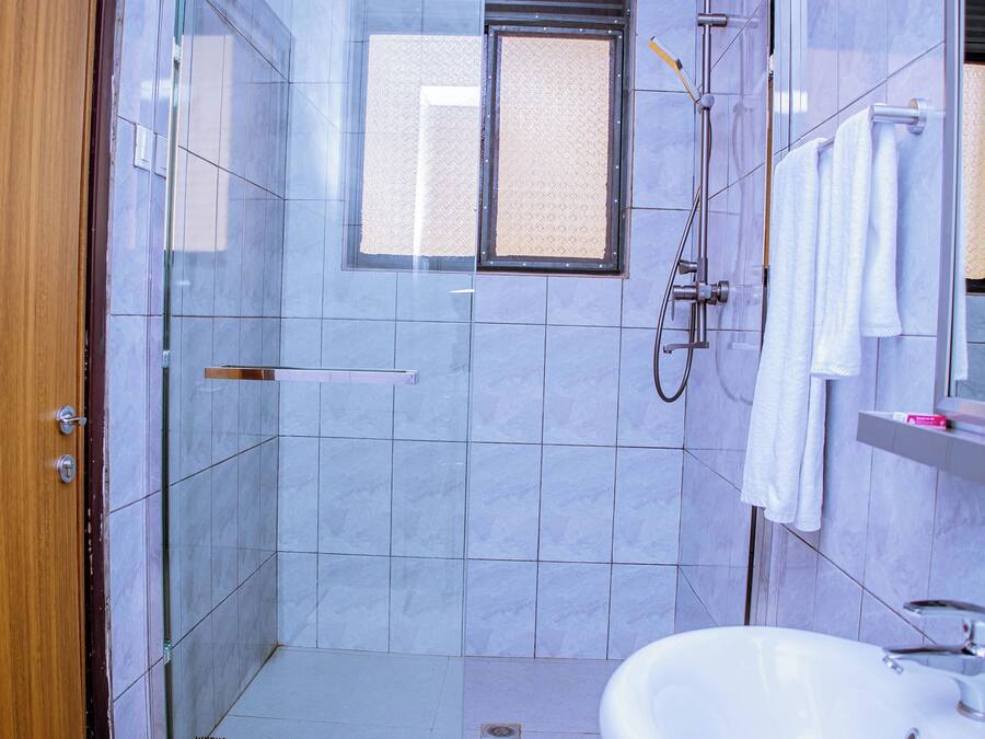 A bathroom with a glass-enclosed shower, a white sink, and a wooden door.