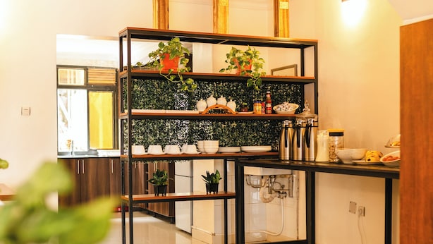 Una cocina moderna con una estantería metálica negra, electrodomésticos blancos y una mesa de madera.