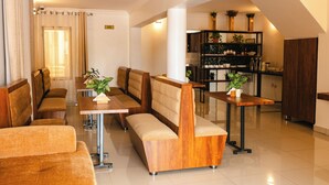 Un moderno vestíbulo de hotel con áreas de estar, una recepción y una cocina al fondo.