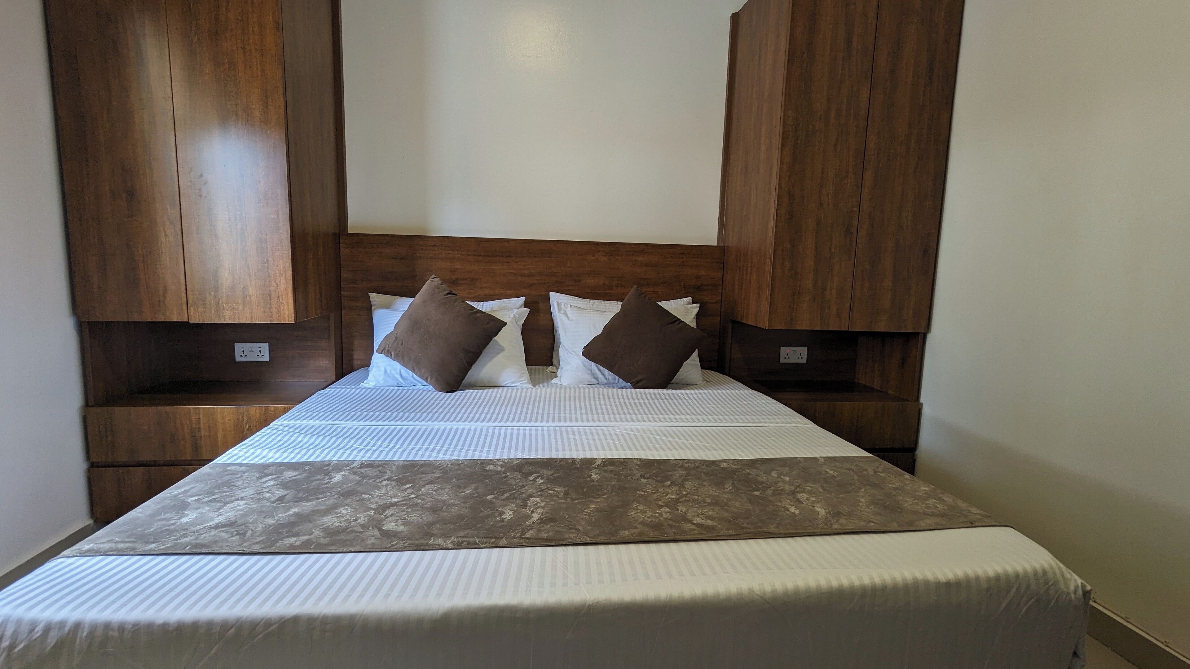 A bed with a headboard, two bedside tables, and a blanket.