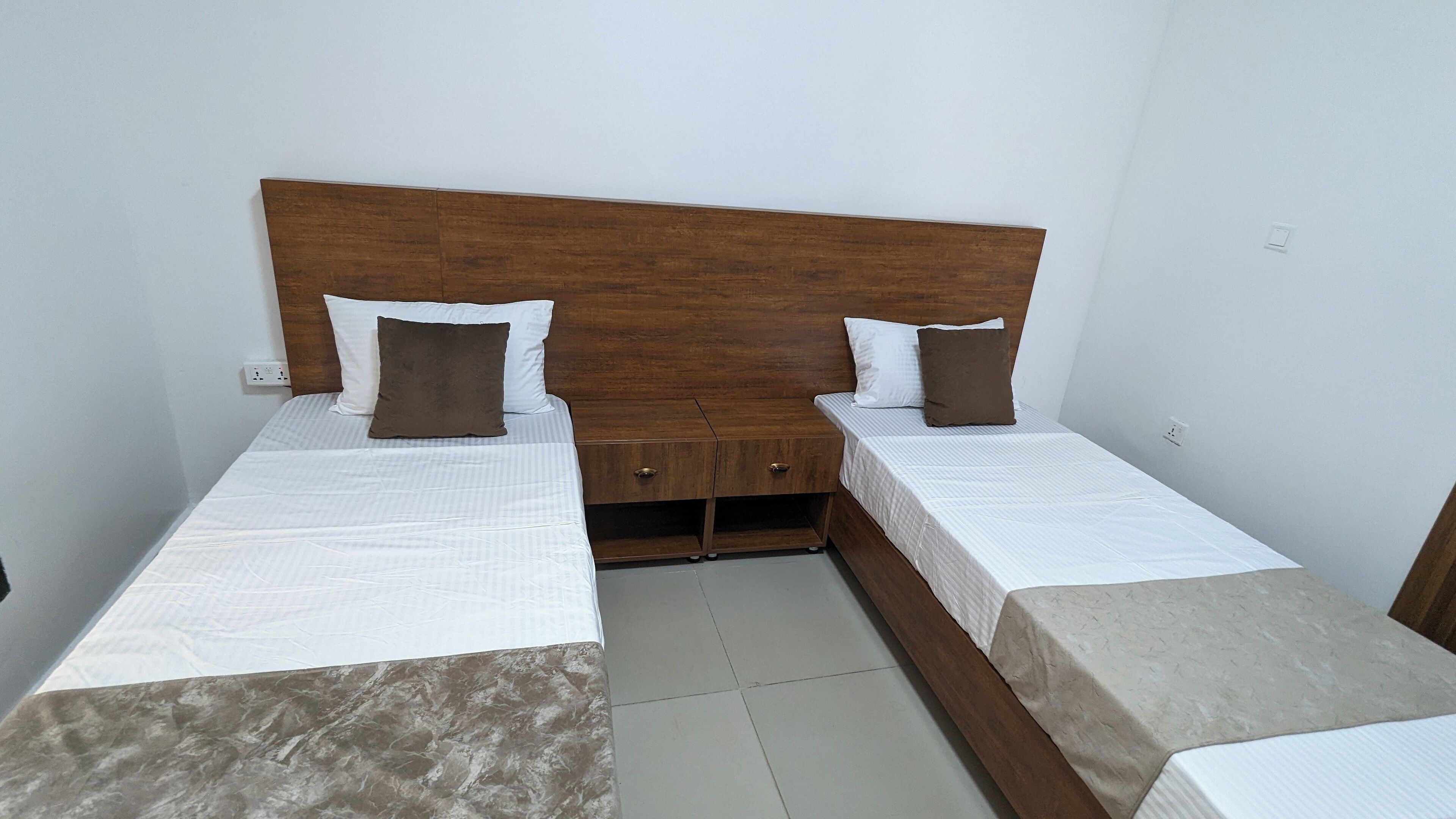 A double bed with a wooden headboard, two bedside tables, and a small drawer unit.