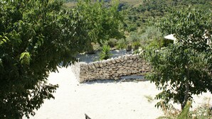 Eine Steinsichtmauer mit einem rustikalen Zaun, umgeben von üppiger Vegetation und einer hügeligen Landschaft im Hintergrund.