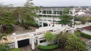Un edificio de varios pisos con fachada blanca, ventanas amplias y un espacio exterior cubierto.
