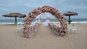 Un arco de boda en la playa con sillas blancas y un dosel blanco.