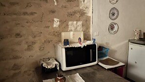 Una cocina con un microondas blanco, una tetera y una cesta sobre la encimera.