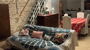 Un dormitorio con cama, escritorio y silla. Se observa una escalera al fondo.