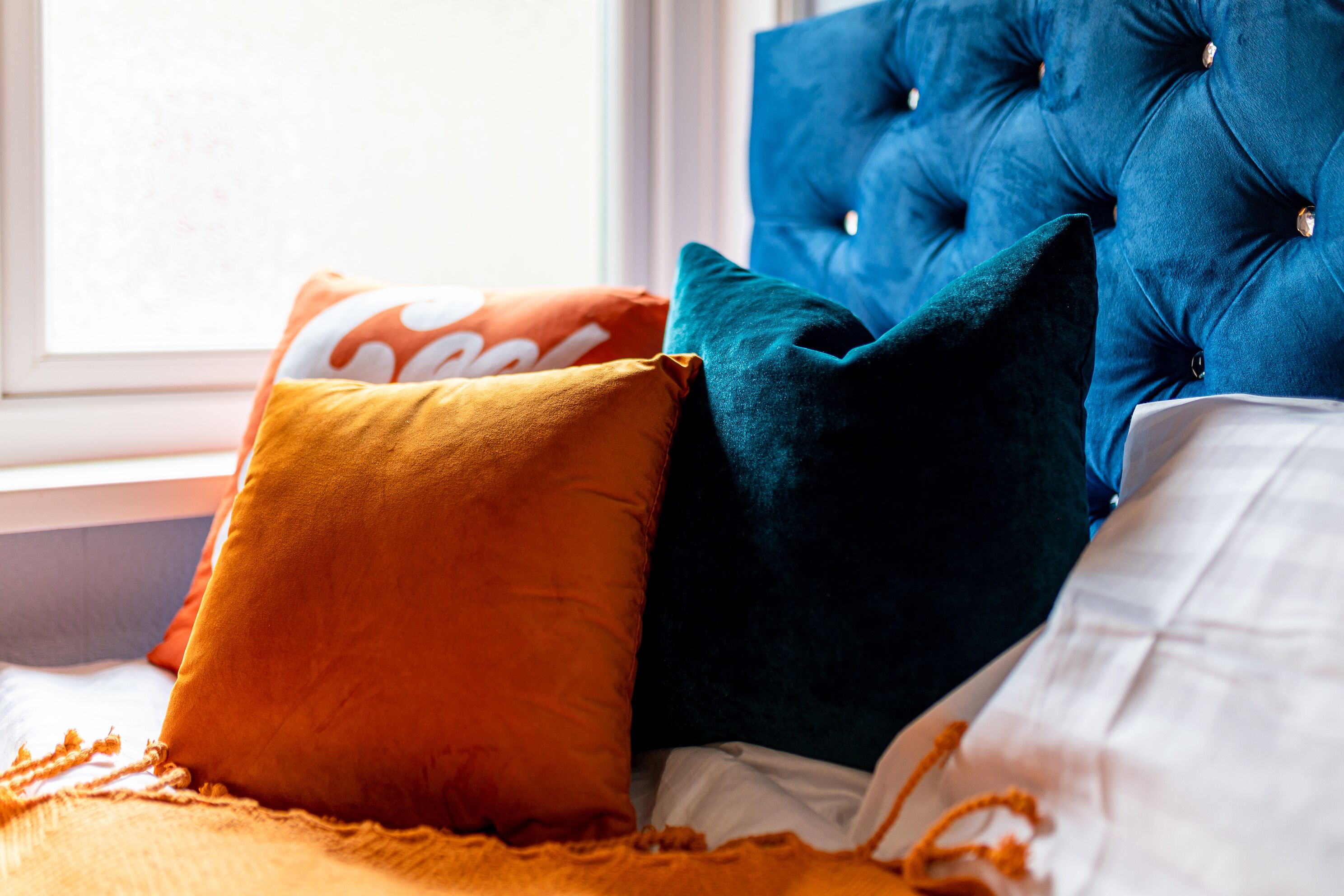 A bed with multiple pillows in various colors.