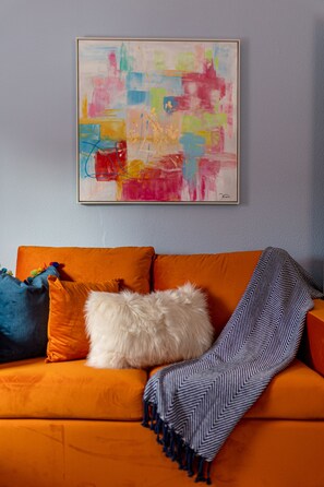 A room with a sofa, pillows, and a blanket.