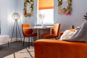 A room with a desk, two chairs, a standing lamp, and a window with a view.