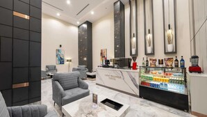A modern lobby with grey sofas, a marble coffee table, a coffee station, and artwork on the walls. - Garden Millennium Hotel - Al-Salamah (Jeddah)