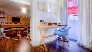 Un salon moderne avec un bureau en bois, un fauteuil bleu, un téléviseur à écran plat et un tapis en peau de vache.