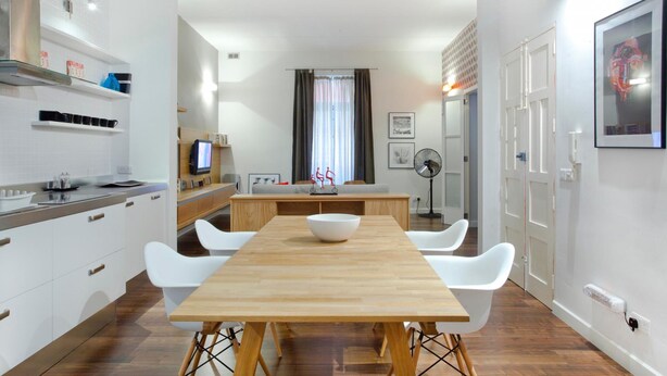Une cuisine moderne avec des meubles blancs, une table à manger en bois et un plan de travail blanc.