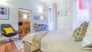 Une chambre à coucher avec un lit, une chaise, un bureau et une fenêtre avec des rideaux.