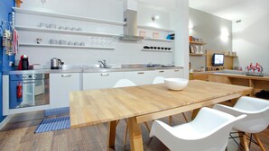 Une cuisine moderne avec des meubles blancs, une table à manger en bois et des chaises blanches.