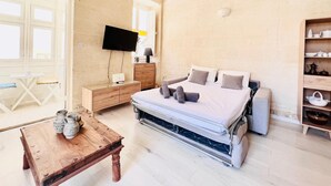 Ein Schlafzimmer mit Bett, Nachttisch, Fernseher und einem Holzschrank.