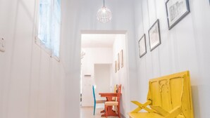 A hallway with a yellow bench, framed pictures on the wall, and a chandelier. - Fairytale - Maltese Balcony - Separate Living Room (Valletta)