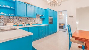 A modern kitchen with blue cabinets, a white countertop, and a chandelier. - Fairytale - Maltese Balcony - Separate Living Room (Valletta)
