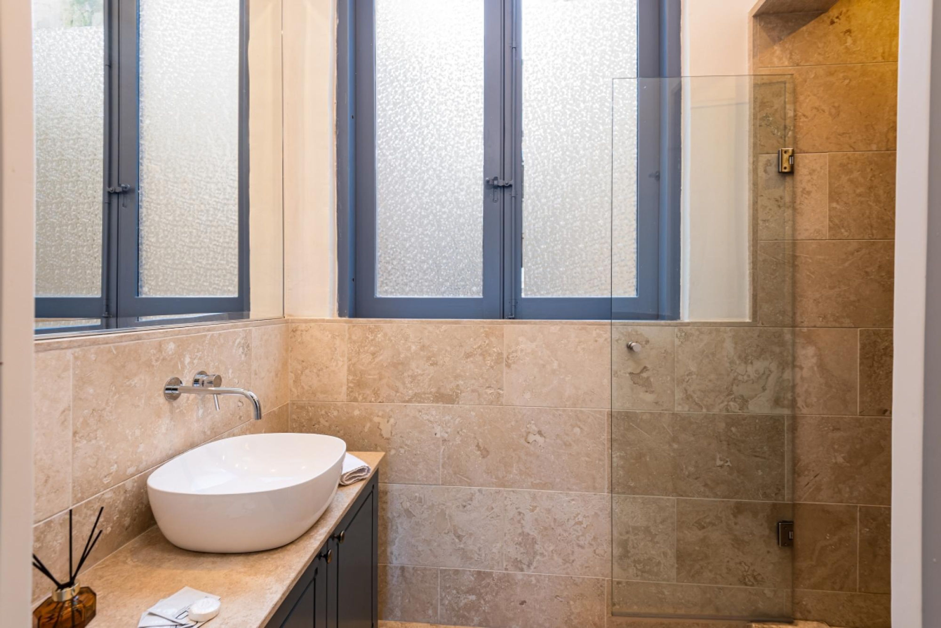 Un bagno con un lavandino grande, finestre smerigliate e cabina doccia.